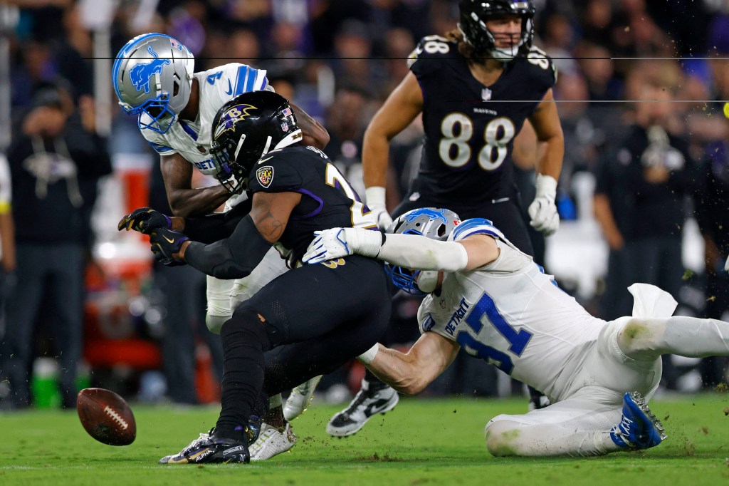 Detroit Lions player (4) tackles Baltimore Ravens player (22) causing a fumble.