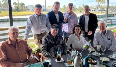 Stockton at table with others, smiling at camera