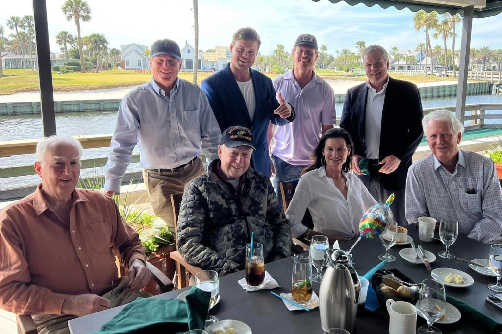 Stockton at table with others, smiling at camera