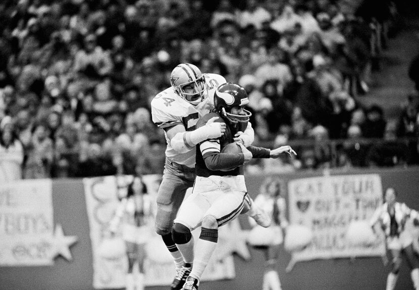 Randy White (54) Dallas Cowboys tackle, wraps his arms around Minnesota Vikings Quarterback...