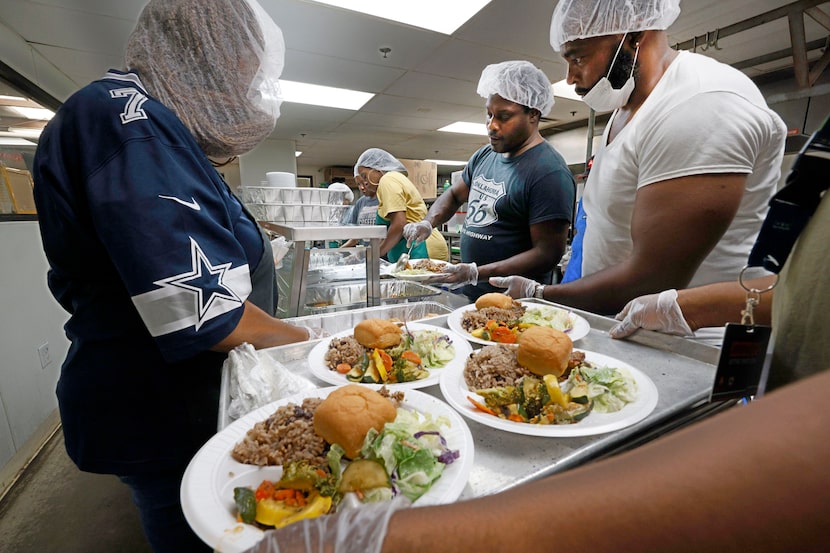 Volunteers Mae Williams, from left, Cedric Davis and Carl Adams prepare plates at the...