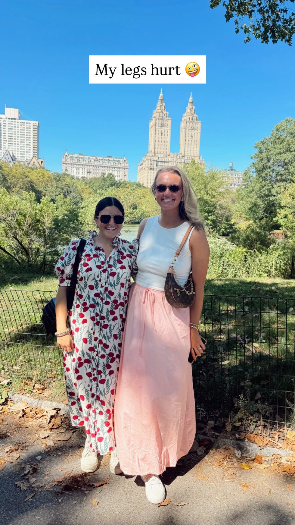 two women standing in a park with tall buildings in the background