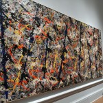 LONDON, ENGLAND - SEPTEMBER 20: A member of staff poses next to a painting by U.S artist Jackson Pollock entitled 'Blue Poles' at the Royal Academy of Arts on September 20, 2016 in London, England. Forming part of the 'Abstract Expressionism' exhibition, it is due to be displayed from September 24, 2016 to January 2, 2017. (Photo by Carl Court/Getty Images)