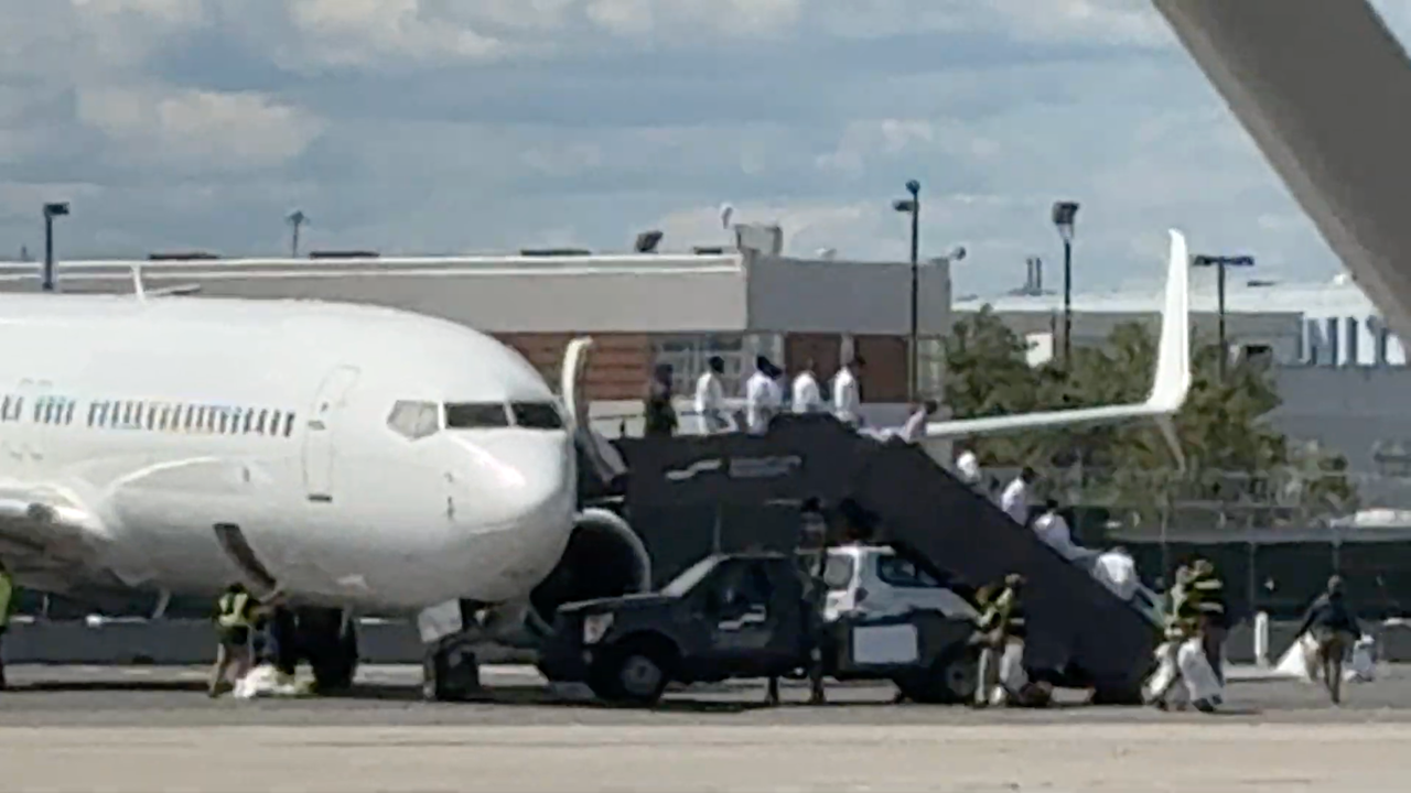 Immigration and Customs Enforcement detainees disembark from an "ICE Air" flight at Newark Liberty International Airport using a set of Signature Aviation boarding stairs.
