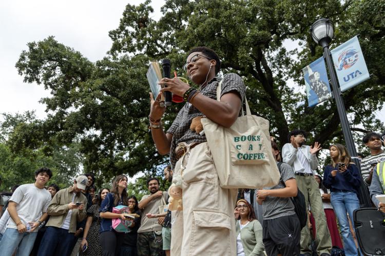 Communications freshman Luke Washington holds up a book during a performative male contest Sept. 24 at the Central Library mall.