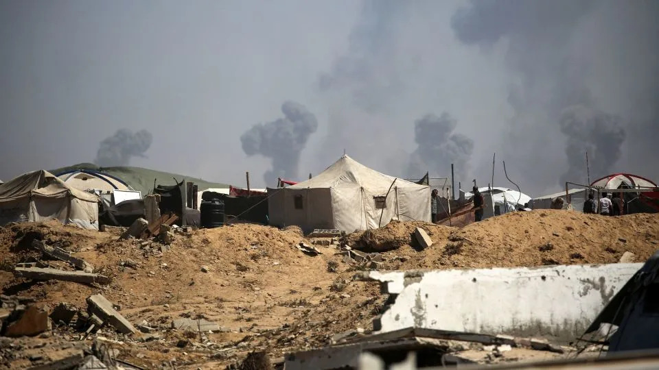 Tents of displaced Palestinians stand in the Nuseirat refugee camp, in the central Gaza Strip, as plumes of smoke rise during Israeli bombardment above Gaza City on Friday. - Eyad Baba/AFP/Getty Images