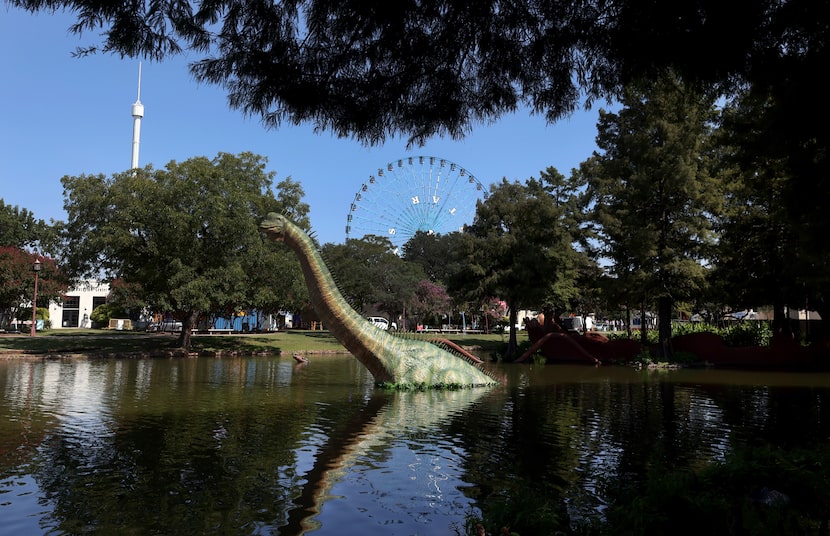 A giant dinosaur structure emerges from the waters of the Lagoon as The Star ferris wheel...