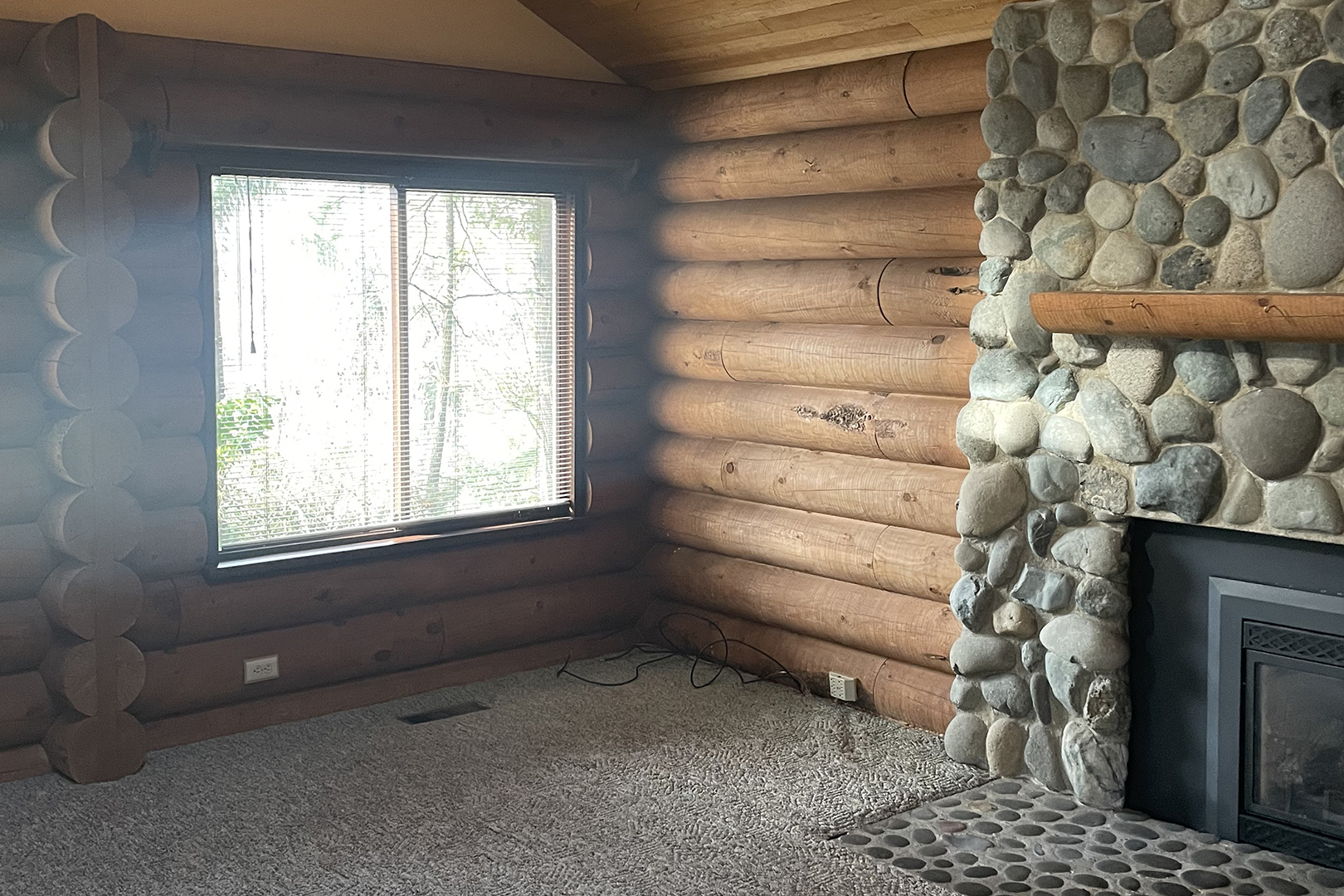 Carpeted living room with stone fireplace