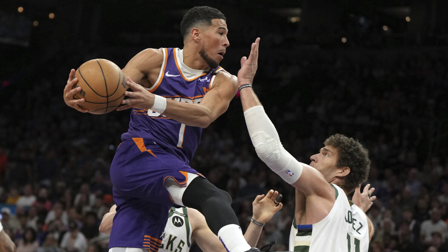 Phoenix Suns guard Devin Booker drives between Milwaukee Bucks guard AJ Green (20) and center Brook...
