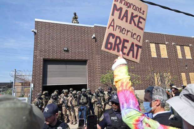 Protesters and activists shout down federal agents while vans enter...