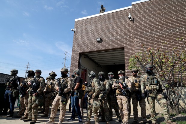 Protesters and activists shout down federal agents while vans enter...
