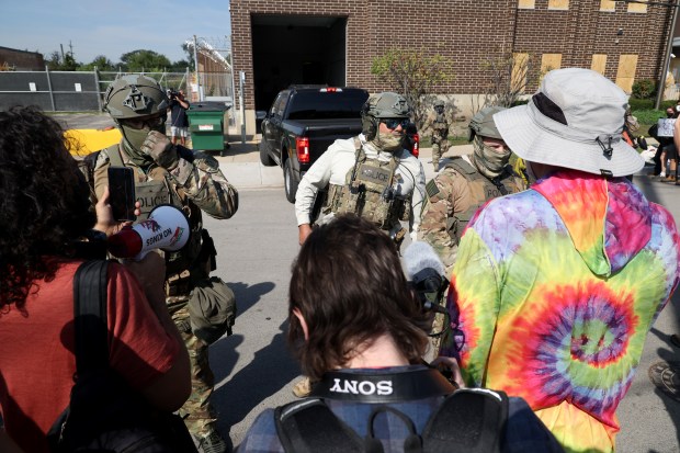 Protesters and activists shout down federal agents while vans enter...