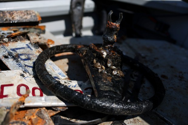 A recovered steering wheel and license plates from sunken cars in the Chicago River sit on the Chaos Divers boat near Cermak Road, Sept. 4, 2025. (Eileen T. Meslar/Chicago Tribune)