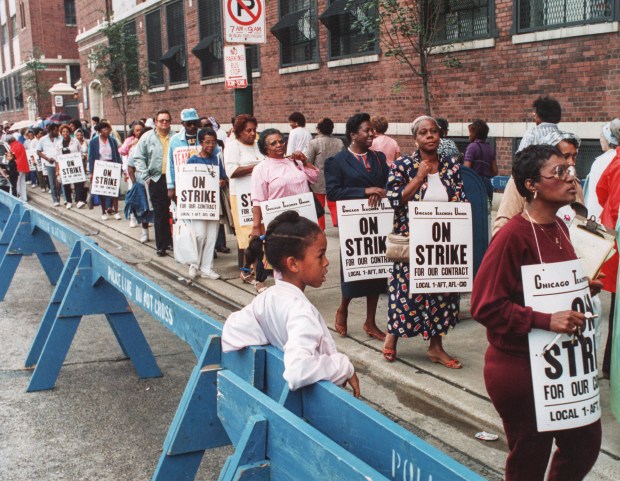 Third-grader, Latoya Shaw, 8, watches as her mother, a teacher's aide, walks in the picket line at the school board office on Sept. 8, 1987. (Chicago Tribune file photo ) (chicago teacher strike) On Sept. 8, 1987, third-grader Latoya Shaw, 8, watches as her mother, a teacher's aide, walks in the picket line at the Chicago school board office. It was the first day of a strike that would last a record 19 days. (Carl Hugare/Chicago Tribune)