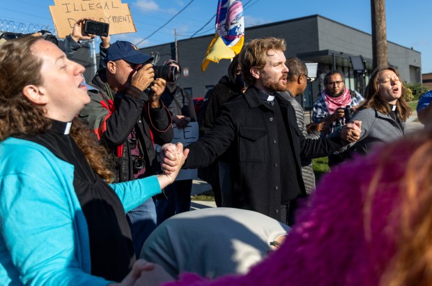 Protesters and activists sit and join hands in front of...