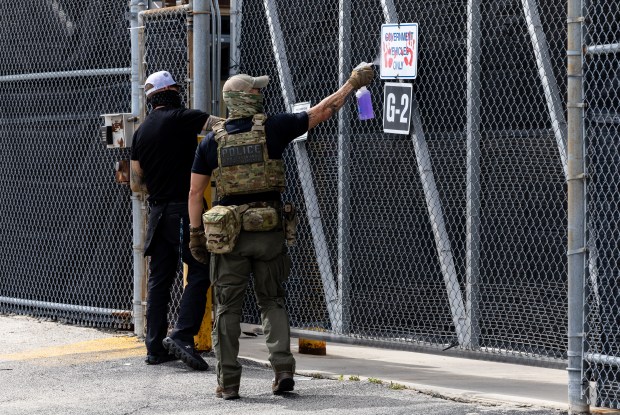 Federal agents clean off markings left by protesters on signs...