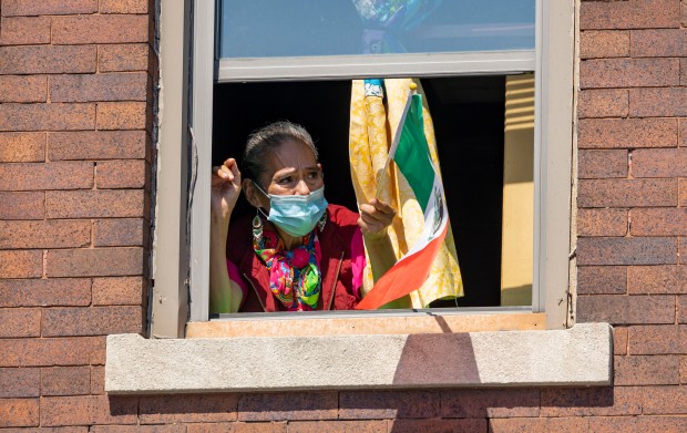 A woman watches from a window during the annual 26th...
