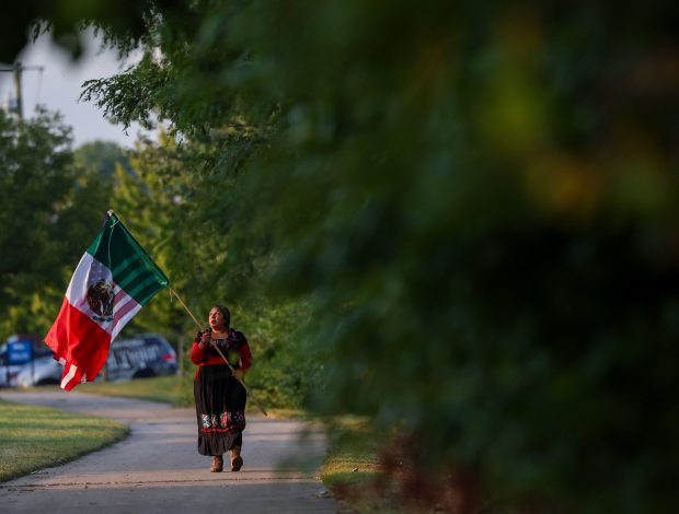 Lina Alvarez, a retired U.S. Army National Guard sergeant first class, carries Mexican and American flags as she makes her way to protest in front of the main gate at the Naval Station Great Lakes on Sept. 10, 2025, in North Chicago. (Stacey Wescott/Chicago Tribune)