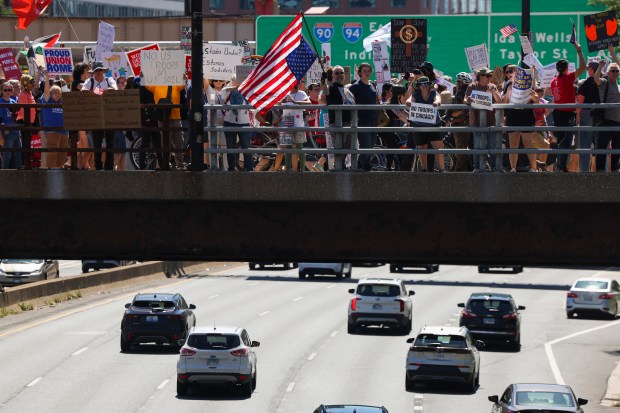 Protesters show their signs to oncoming traffic on I-90 as they march on West Fulton Street during the Workers Over Billionaires march in the West Loop on Sept. 1, 2025. (Eileen T. Meslar/Chicago Tribune)
