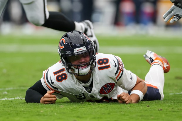 Bears quarterback Caleb Williams falls on the field after being...