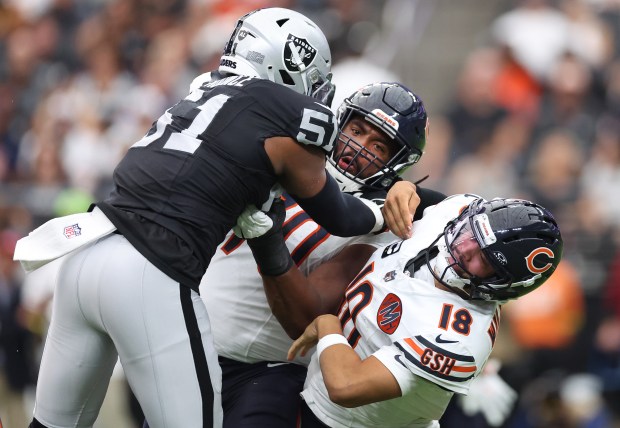 Chicago Bears quarterback Caleb Williams (18) is pushed down after...