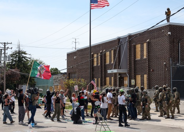 Protesters yell at federal agents while they clear a path...