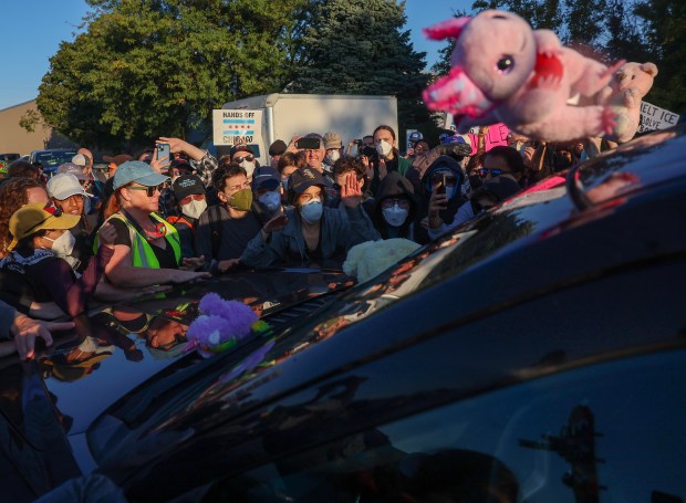 Protesters surround the SUV of a federal agent and try and prevent him from driving down Harvard Street to the US Immigration & Customs Enforcement facility on Sept. 26, 2025, in Broadview. Protesters and federal agents faced off throughout the morning. Federal agents used several kinds of chemical gasses, baton rounds, and arrested at least two people while protesters refused to clear the street. (Stacey Wescott/Chicago Tribune)