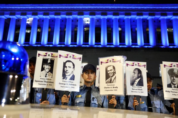 Chicago Police Department recruit Alfonso Ambriz stands among other recruits while holding up images of some of the 607 fallen Chicago police officers during the Chicago Police Memorial Foundation's annual candlelight vigil at the Gold Star Families Memorial on Sept. 10, 2025. (Chris Sweda/Chicago Tribune)