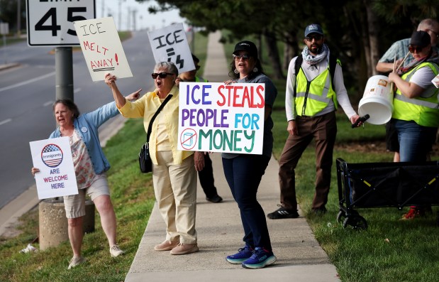 A small group of people protest against federal immigration agents outside of a Hampton Inn hotel in Downers Grove where agents are reportedly staying, on Sept. 9, 2025. From left, Emily Ellsworth, of Wheaton, her sister Penny Ellsworth, of Glen Ellyn, and Katie Scott, of Naperville, were among the 8 people protesting. (Chris Sweda/Chicago Tribune)