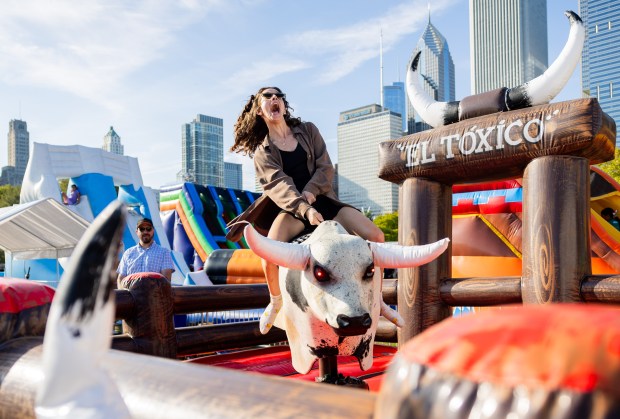 Libby Ebeling rides a mechanical bull at El Grito Chicago at Grant Park's Butler Field in Chicago on Sept. 14, 2024. (Tess Crowley/Chicago Tribune)