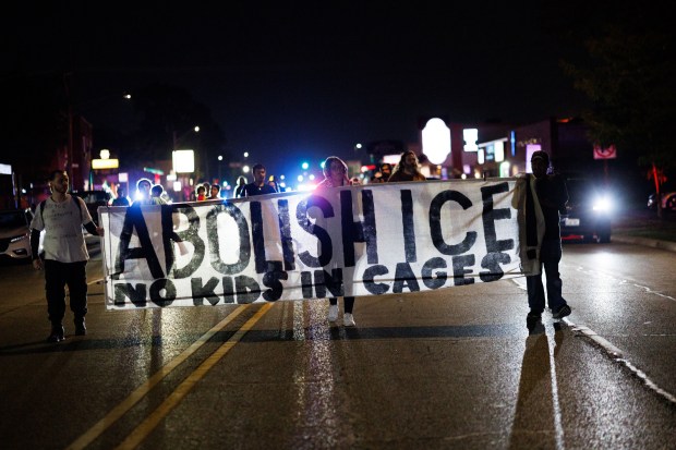 People march in the street on West Grand Avenue in...