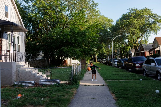 Venezuelan migrant Pedro Mendez plays with a basketball outside his home during the Fourth of July holiday in the Englewood neighborhood, July 4, 2024 in Chicago. (Armando L. Sanchez/Chicago Tribune)