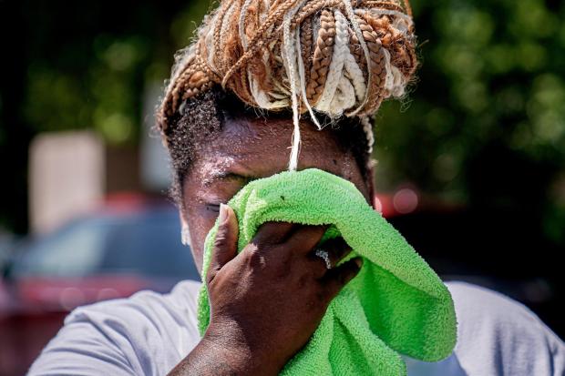 FILE - Nicole Brown wipes sweat from her face while setting up her beverage stand near the National Mall on July 22, 2022, in Washington. (AP Photo/Nathan Howard, File)