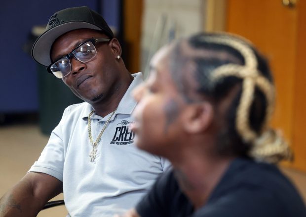 Cedric Hawkins, left, an outreach supervisor with the violence prevention organization Chicago CRED, listens as Chrischauna Smith talks about her past run-ins with the law and how working with CRED has helped turn her life around, Sept. 11, 2025. (Terrence Antonio James/Chicago Tribune)
