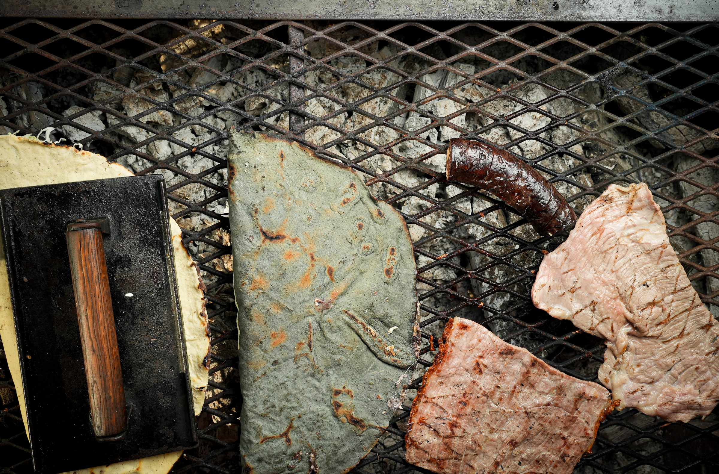 Blue corn and yellow corn tlayudas on the mesquite grill with thin flank steak at Poncho’s. 
