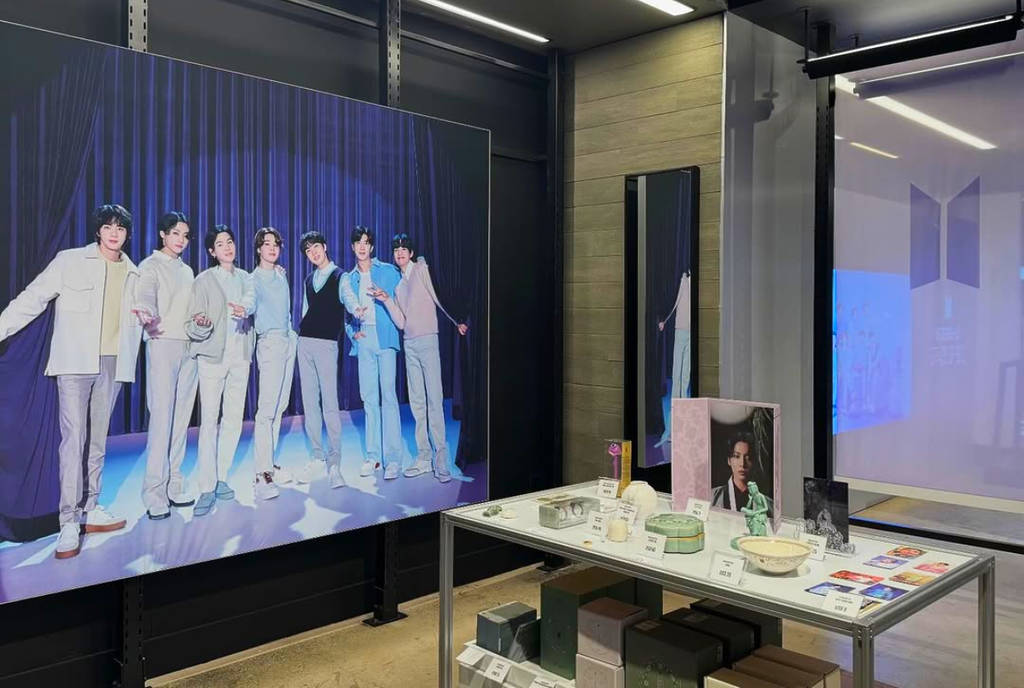 Image shows a display of K-Pop group BTS and display table at the Spaces of BTS pop-up in Houston Galleria.