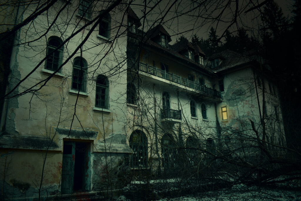 Image shows the front facade of a haunted house at nightfall.
