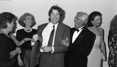Actor Richard Gere shows designer Giorgio Armani his suit label, as guests watch the exchange, with socialite Lee Radziwill.