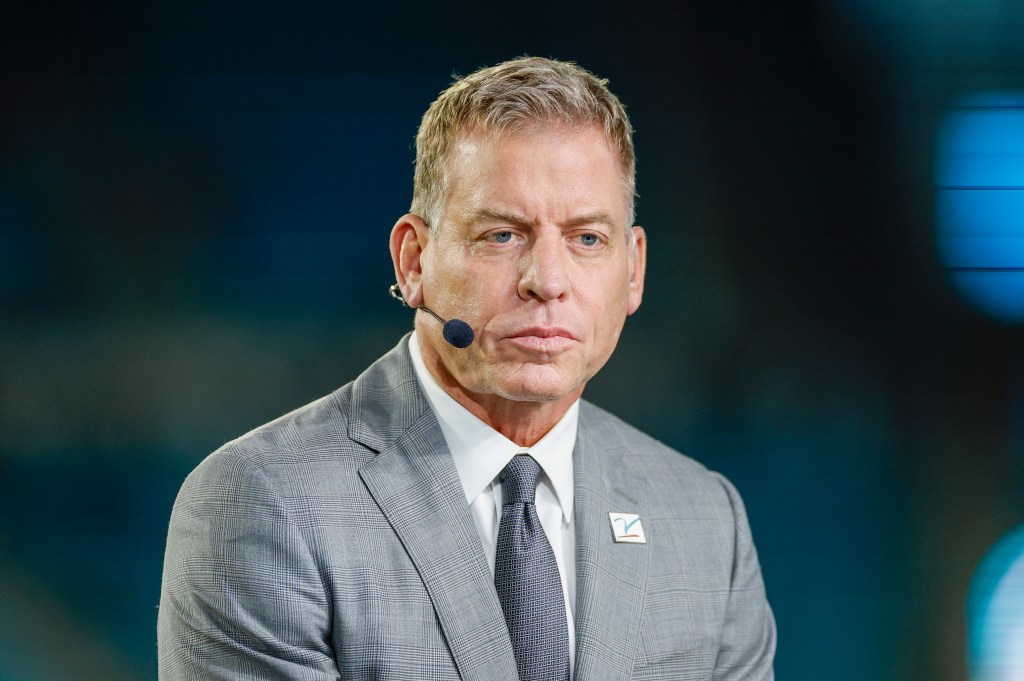 Close-up of a man in a gray suit speaking into a microphone.
