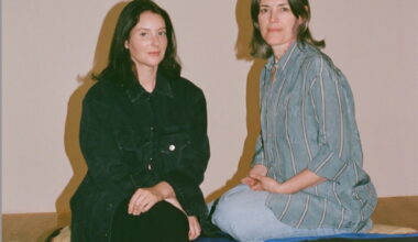 Two women seated on a gallery floor.
