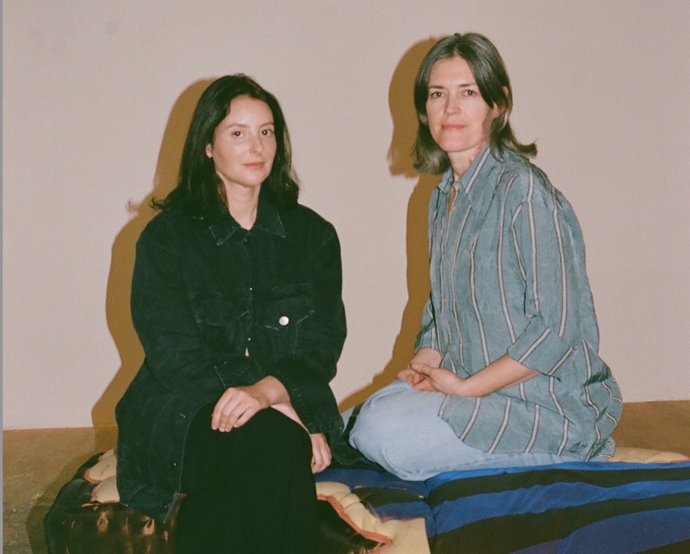 Two women seated on a gallery floor.