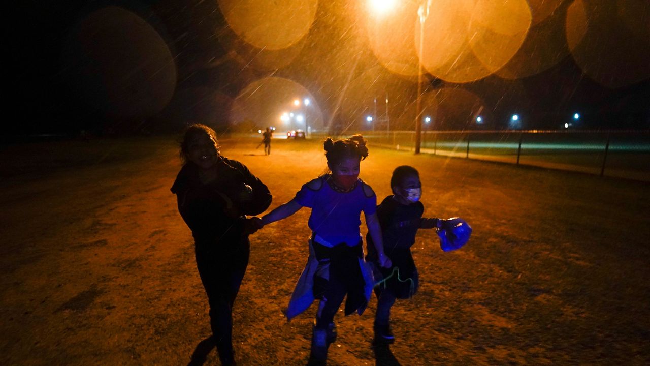 Young migrants hold hands as they run in the rain at an intake area after turning themselves in upon crossing the U.S.-Mexico border in Roma, Texas, May 11, 2021. (AP Photo/Gregory Bull)