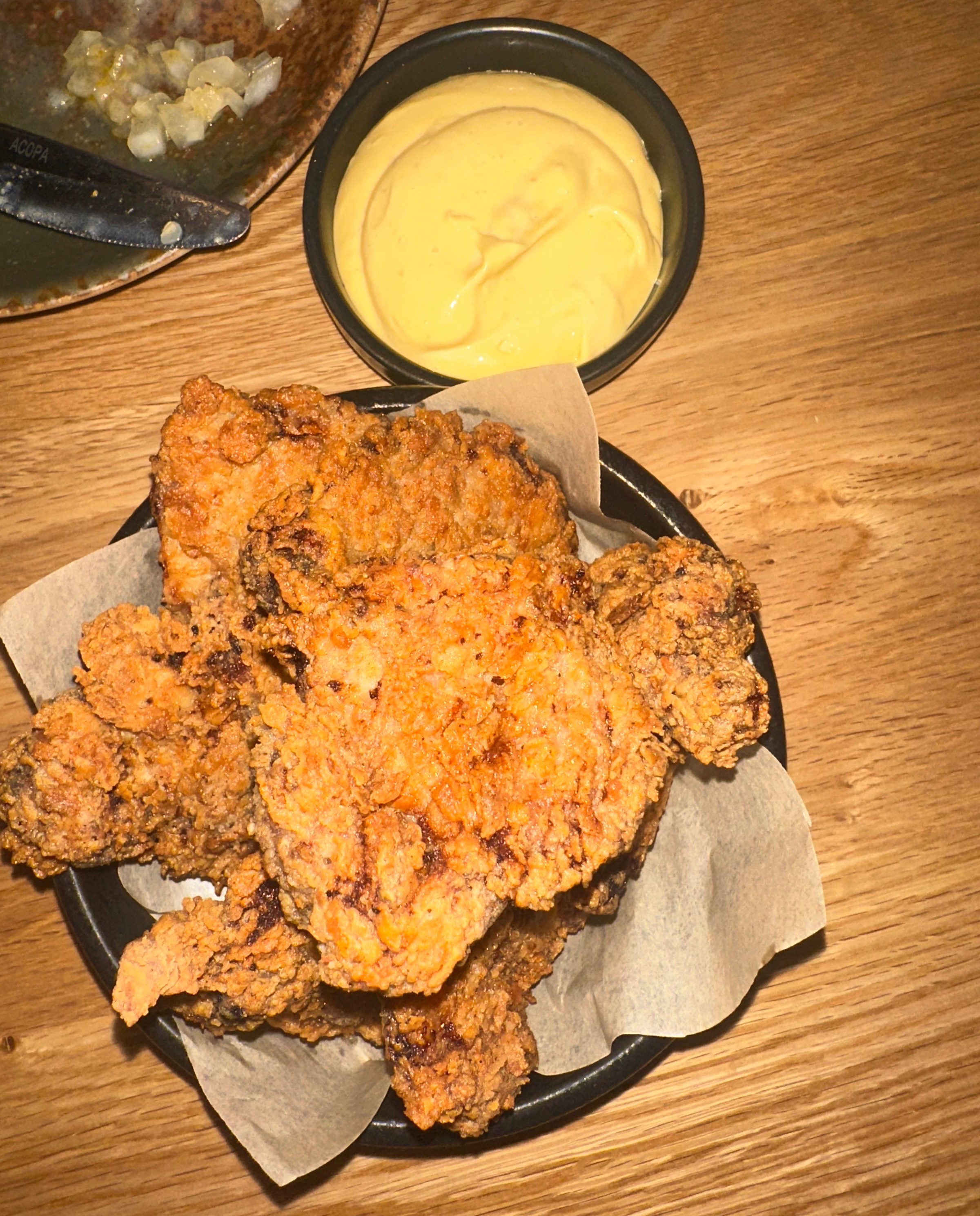 A plate of fried chicken next to a saucer of yellow sauce.
