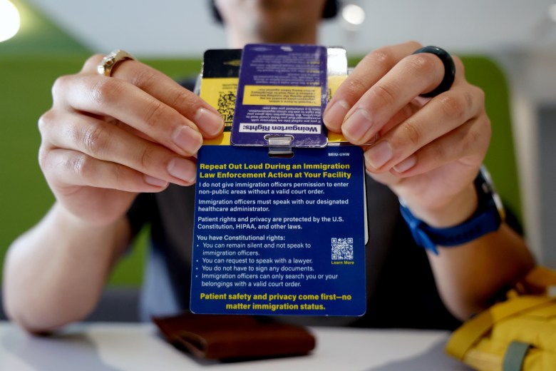 Close-up of hands holding a blue laminated card with immigration rights information.