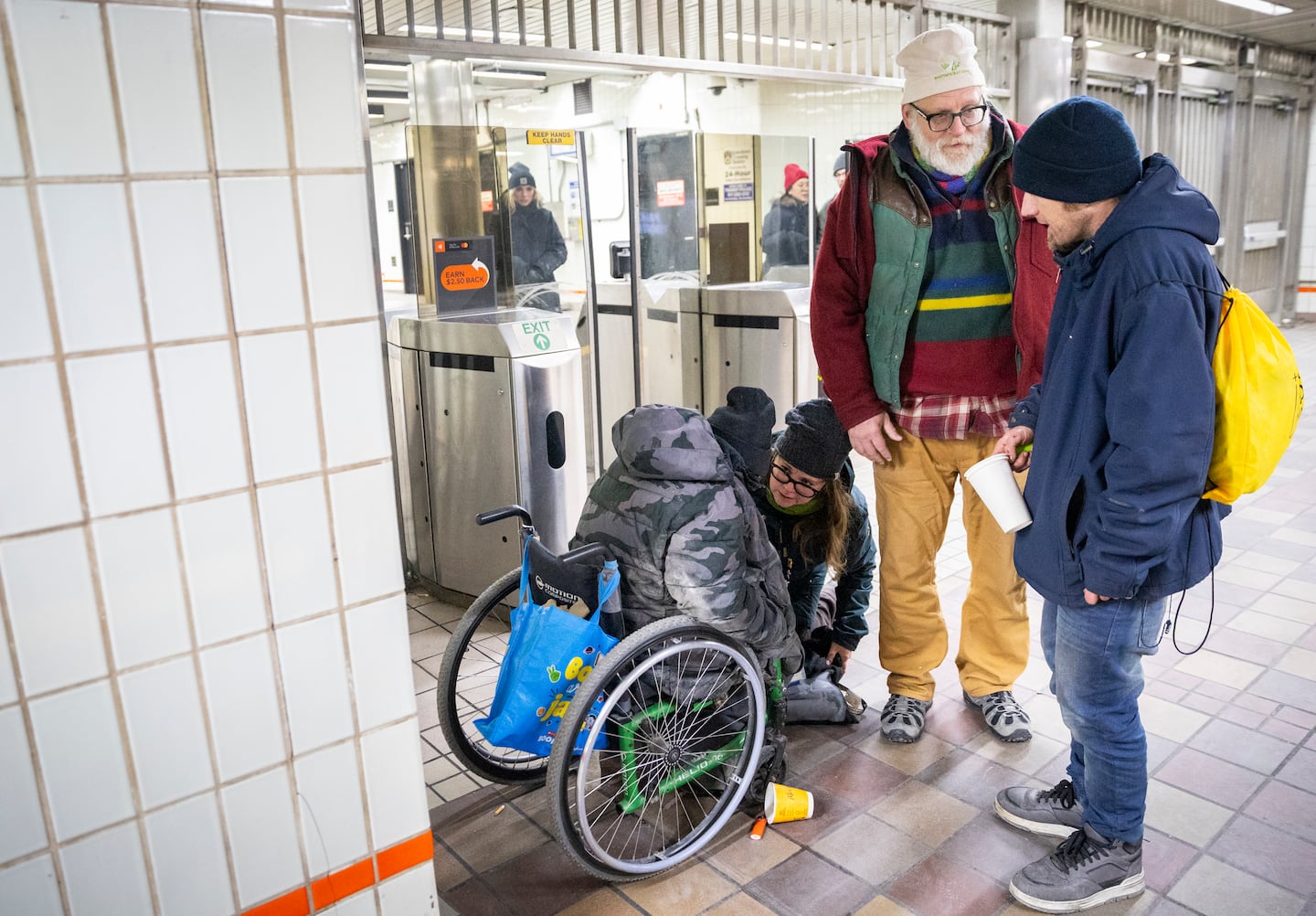 Beckie Tachick, a nurse with the Boston Health Care for the Homeless Program, left kneeling, and Jim Greene, Assistant Director for Street Homelessness Initiatives, Mayor’s Office of Housing, City of Boston, right standing, conduct welfare checks at the Temple Place MBTA Station on Thursday, Jan. 30, with Patrick, far left, and Danny, far right, during the annual homeless count.