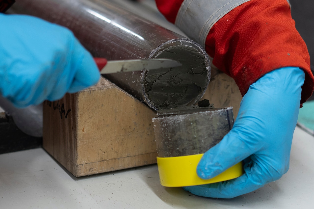 A knife cuts through a cylindrical tube.
