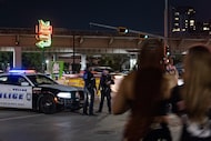 Dallas Police Officers Keyon Valentine and Michael Pullia stand near a patrol vehicle...