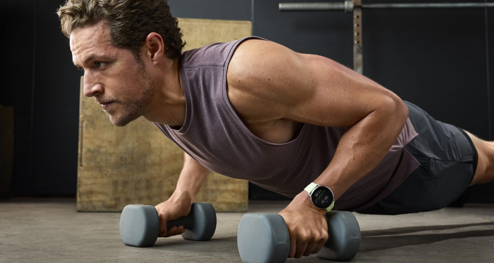 A photo of the Garmin Venu 4 on a man's wrist as he does weighted push-ups.