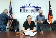 Mayor Deb Rushing reviews a document as council members Eric Maloy (left) and Mick Medlin...