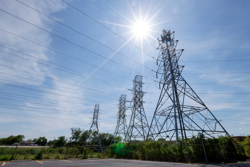 The sun is seen over long-distance transmission power lines, Monday, Aug. 19, 2024, in Fort...